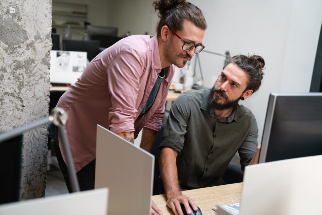 Diverse group of professionals meeting in office. IT programmers use computer, talk strategy. Specialists create innovative software. Engineers develop inspirational app